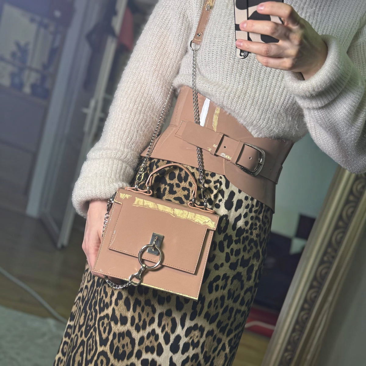 Aria Margo mocha patent leather hourglass corset belt worn over a cream sweater and leopard print skirt