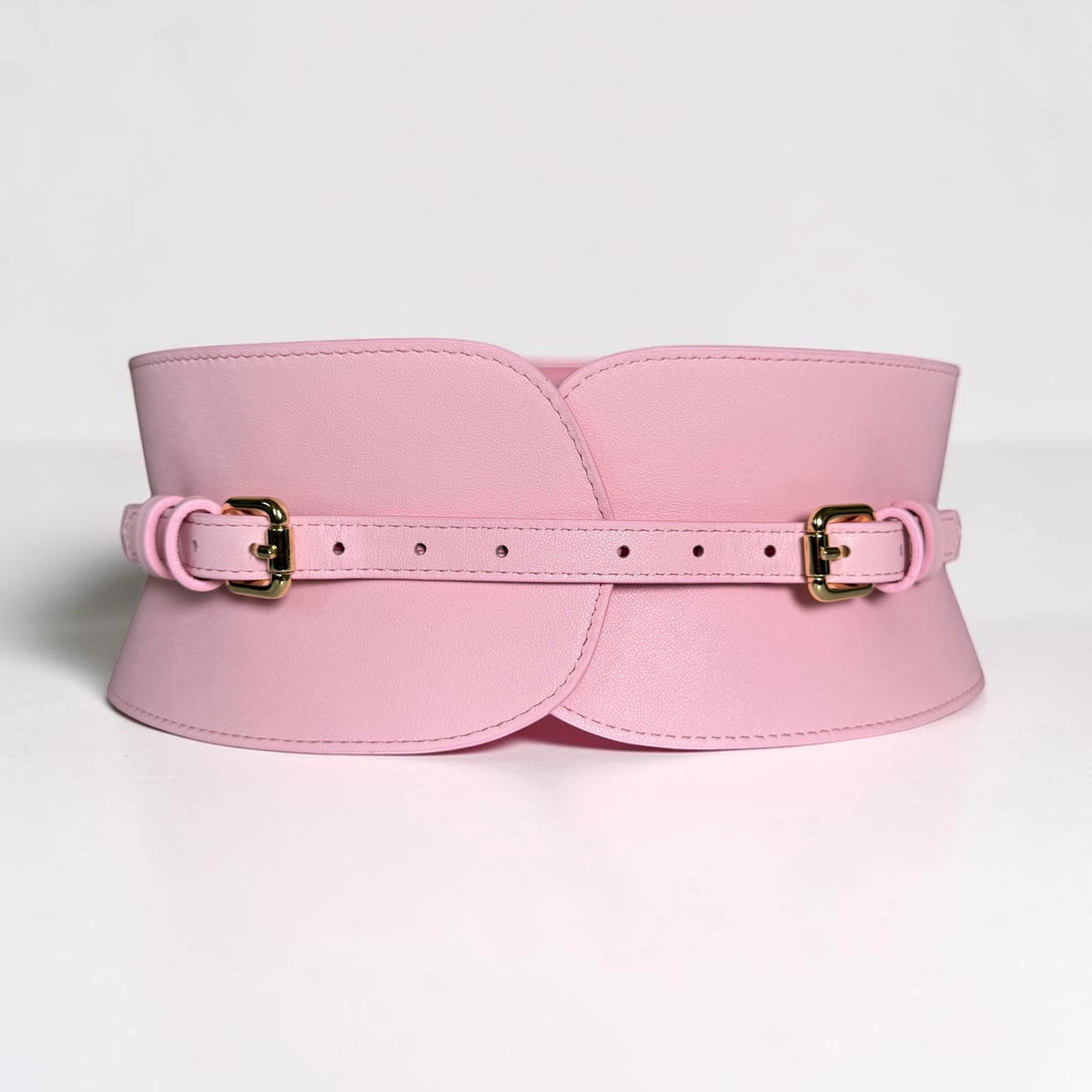 Aria Margo pale pink leather corset belt with gold buckles and a structured waist-defining design.