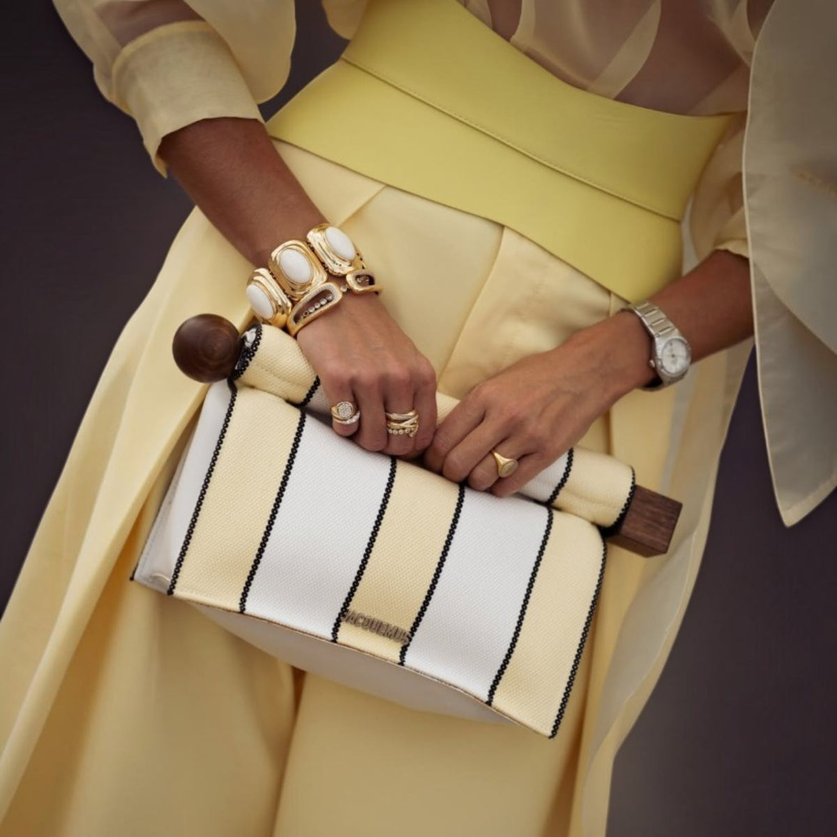 Aria Margo pale yellow leather corset belt worn over a matching yellow outfit with a striped handbag