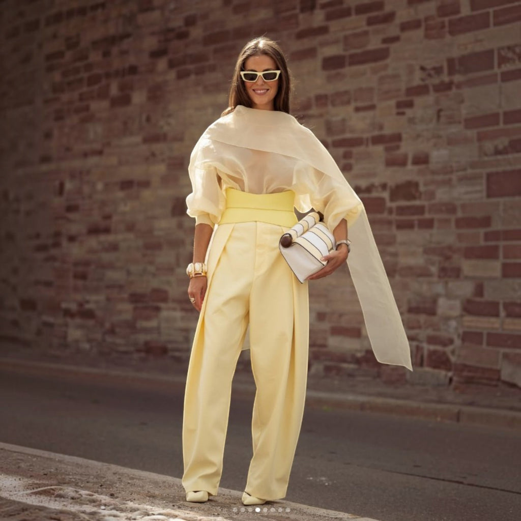 Aria Margo pale yellow leather corset belt worn over a matching yellow outfit with a sheer blouse and trousers