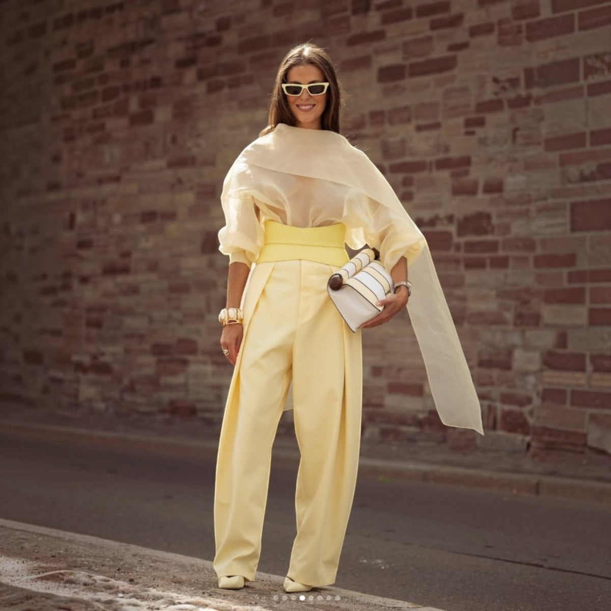 Aria Margo pale yellow leather corset belt worn over a matching yellow outfit with a sheer blouse and trousers