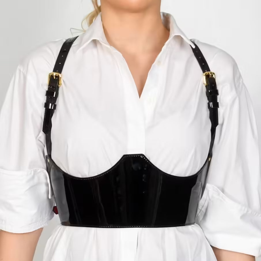 Aria Margo black patent leather under-bust belt with adjustable shoulder straps worn over a white shirt.