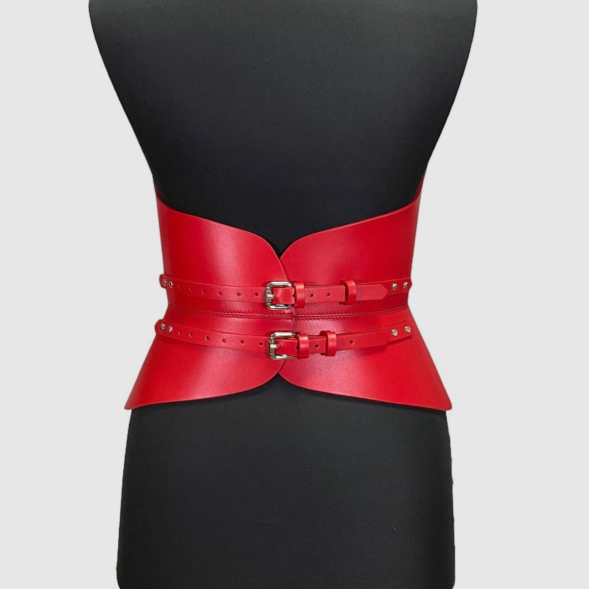 Aria Margo red Italian leather corset belt with two front buckles on a mannequin, highlighting a waist silhouette.