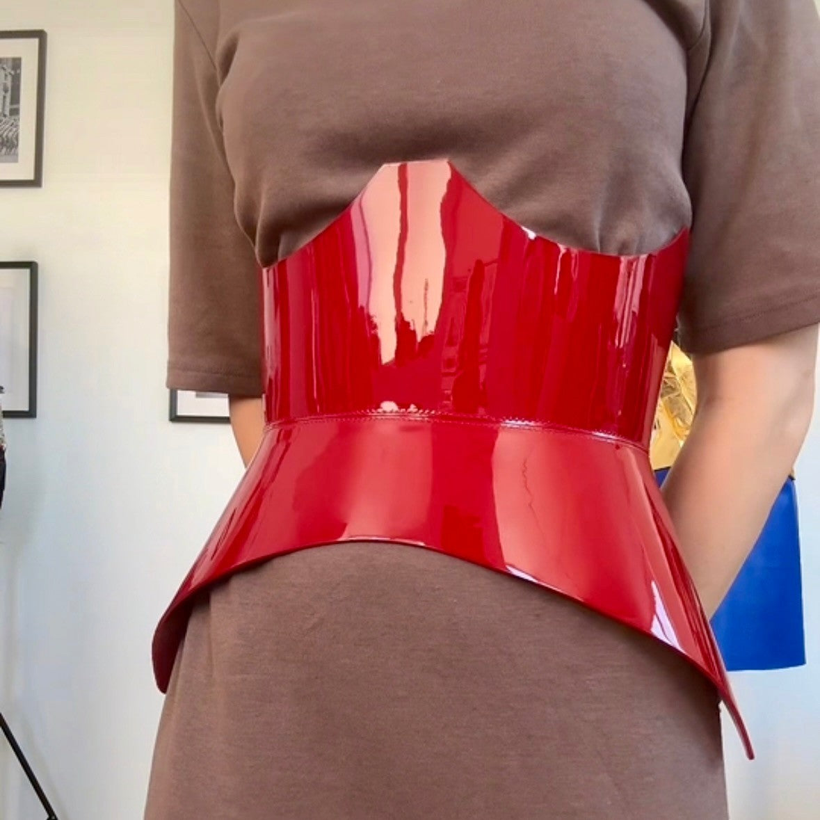 Aria Margo red patent leather corset belt with a high-shine finish, worn over a brown t-shirt dress.