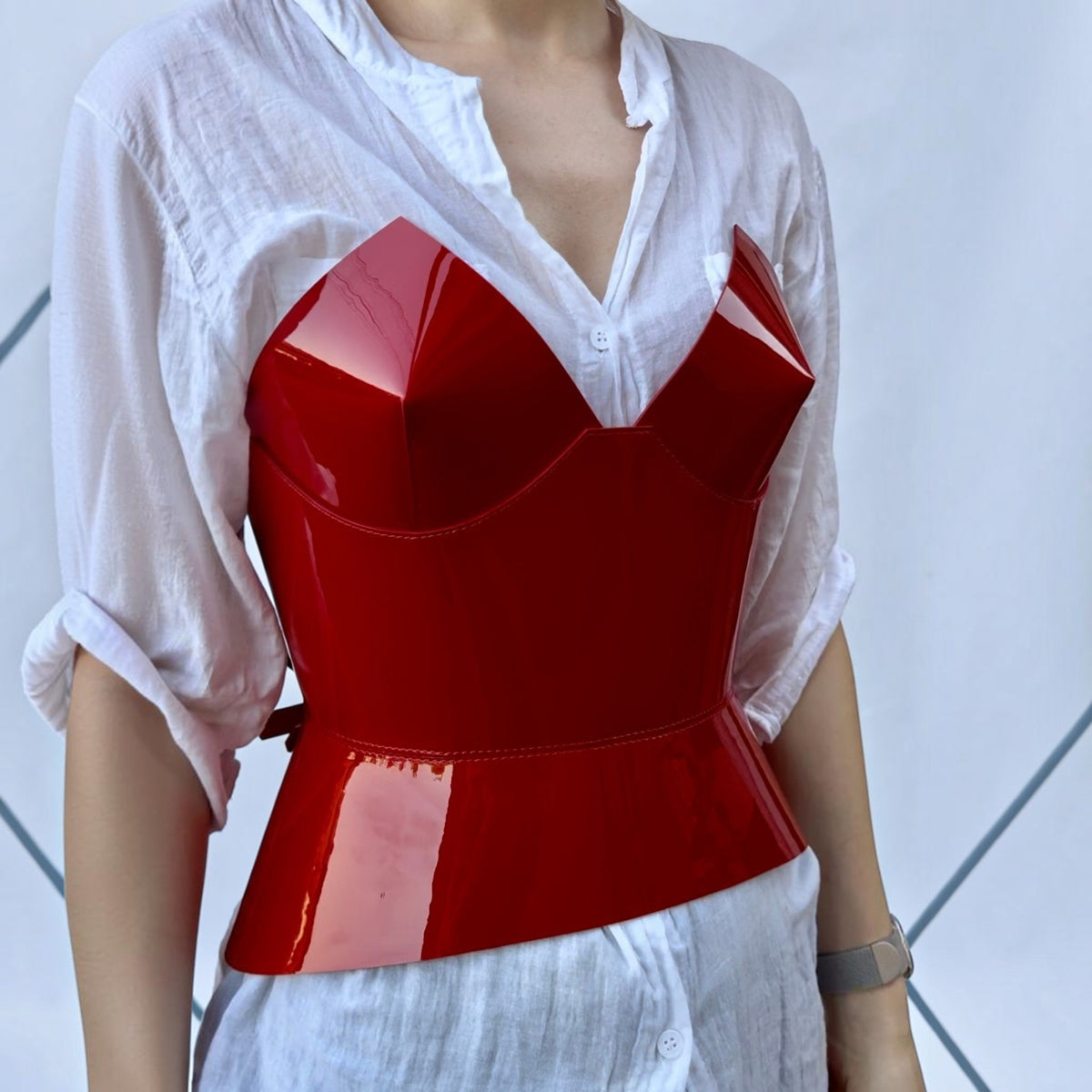 Aria Margo red patent leather corset with a structured round body design worn over a white button-down shirt.