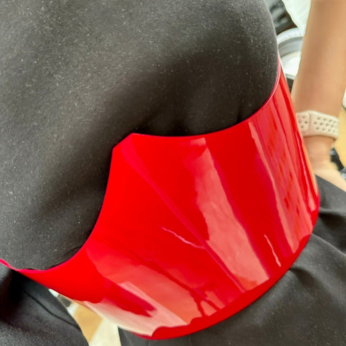 Aria Margo red patent leather under-bust belt worn over a black top, featuring a high-shine finish.