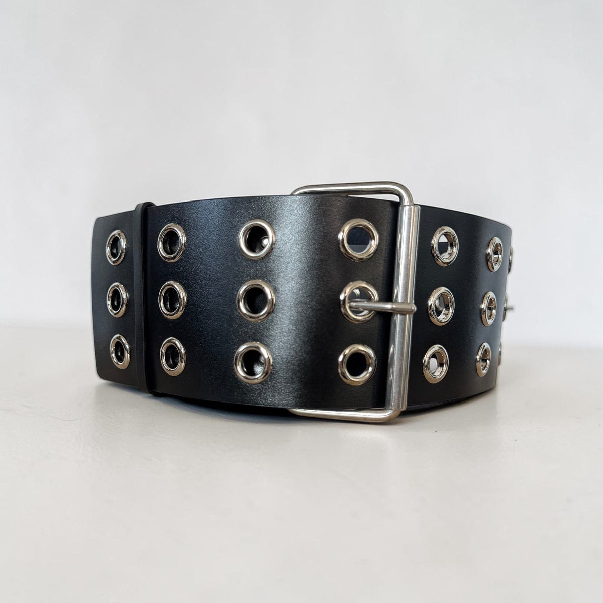 Aria Margo Test black leather coat belt featuring three rows of silver eyelets and a double-prong buckle.