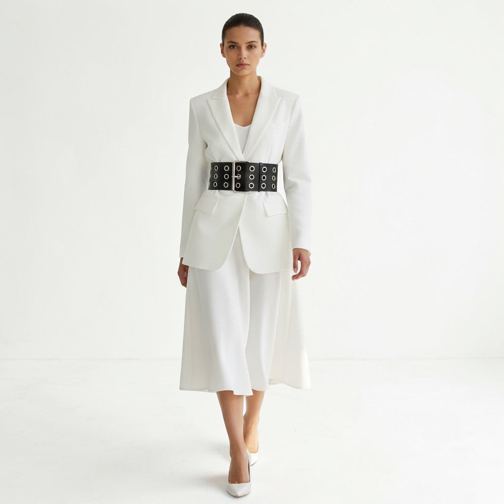 Aria Margo Test black leather coat belt with silver eyelets and double-prong buckle worn over a white blazer and skirt