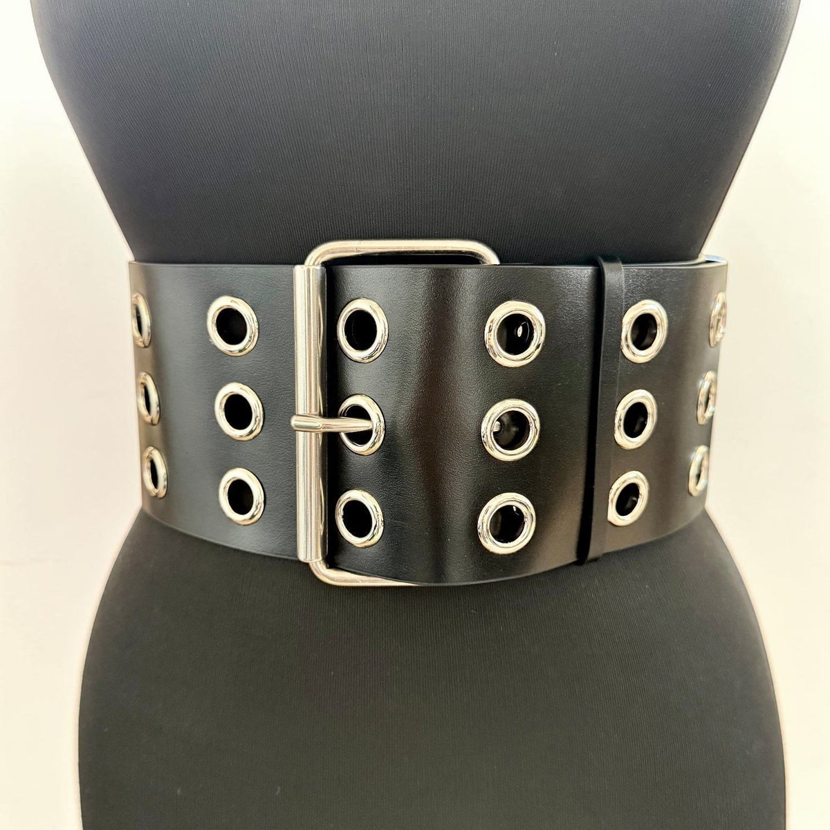 Aria Margo Test black Italian leather wide coat belt with silver eyelets and a double-prong buckle on a mannequin.