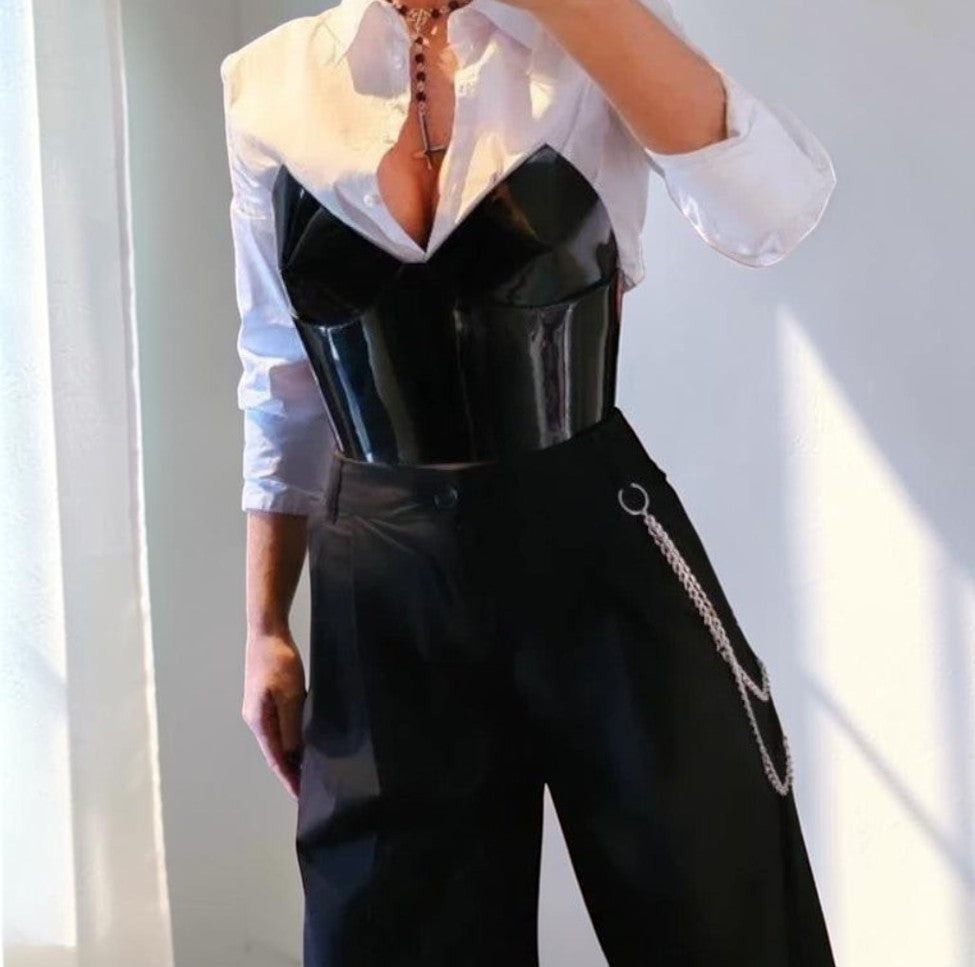 Aria Margo Test black patent leather over-bust corset worn over a white button-down shirt and black trousers