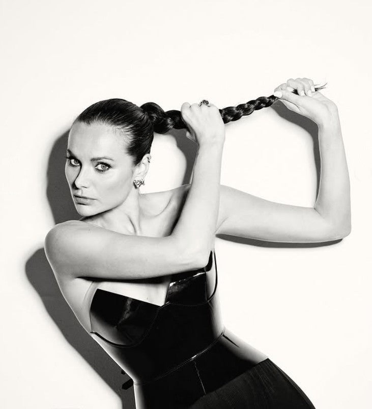 Aria Margo Test black patent leather corset belt with a high-shine finish worn by a woman with a braided ponytail.