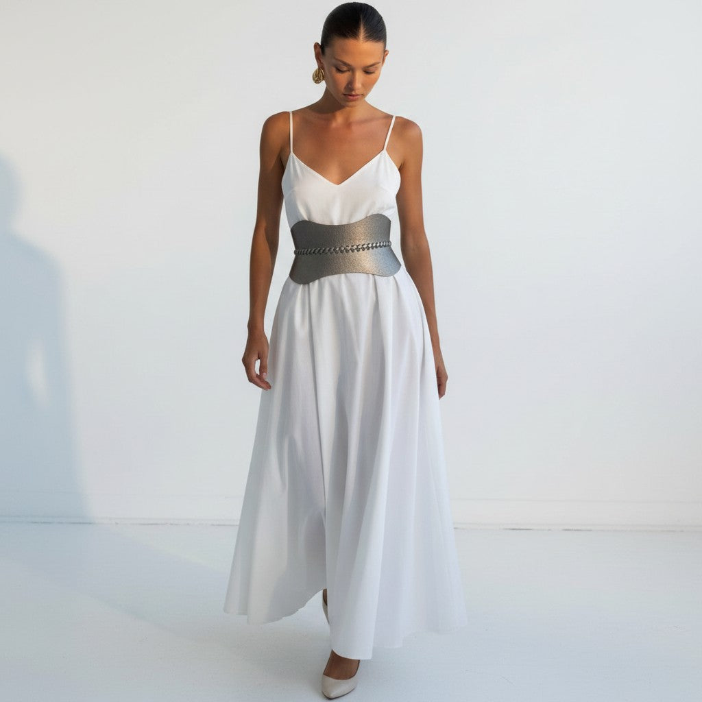 Aria Margo Test silver metallic leather corset belt worn over a white maxi dress to define the waist.