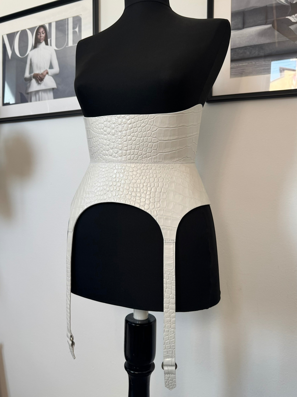 Aria Margo white croco leather corset belt with long garter straps on a black mannequin torso.
