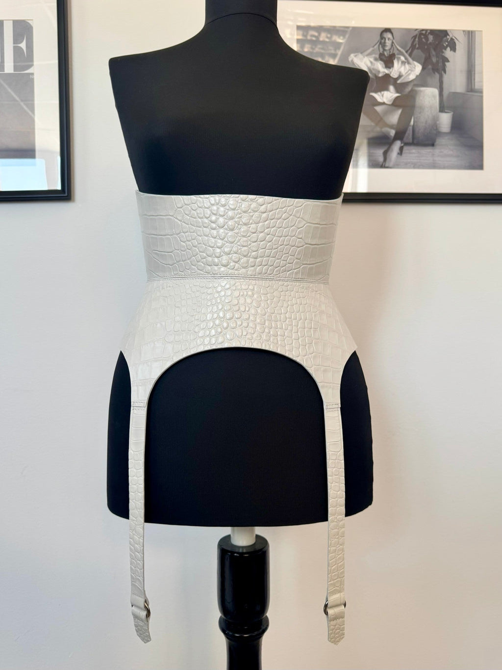 Aria Margo white croco leather corset belt with long garter straps on a black mannequin torso.