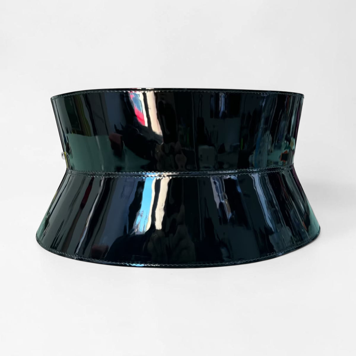 Aria Margo wide black patent leather corset belt with a high-shine hourglass silhouette on a marble surface.