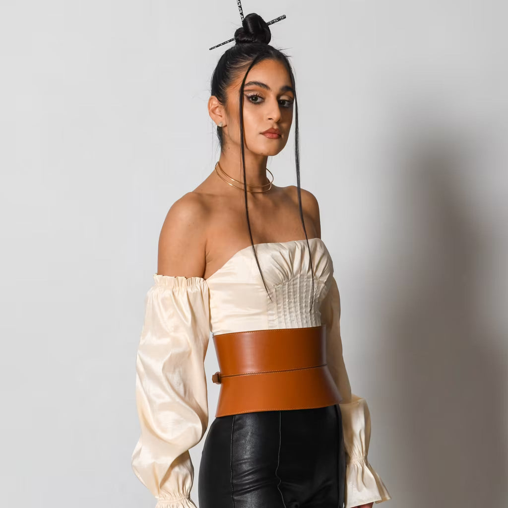 Aria Margo wide brown Italian leather corset belt with adjustable buckles worn over a cream off-shoulder top.